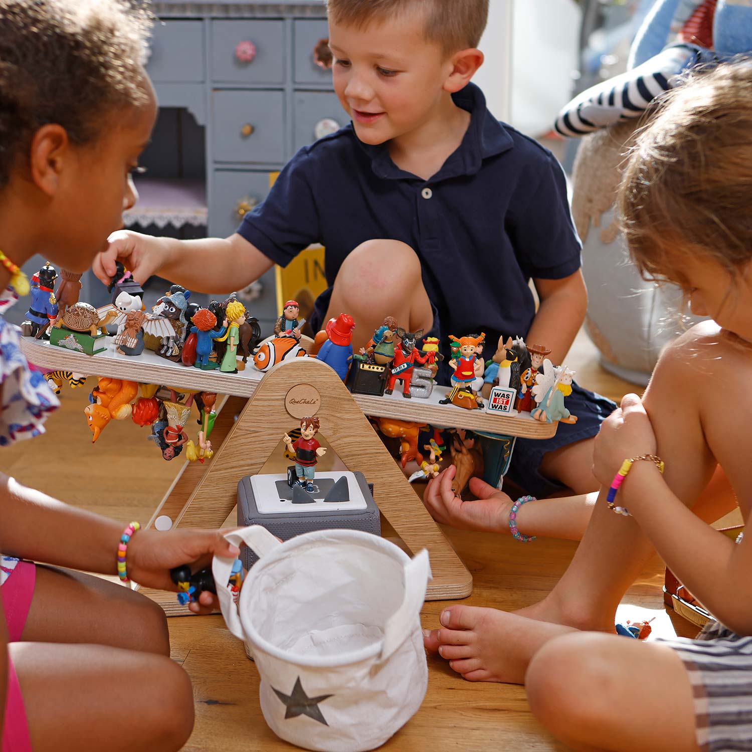 Drei Kinder spielen mit Tonie-Figuren rund um ein Tonie-Regal