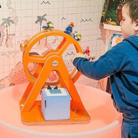 Glück-auf-Rad in neon-orange mit einem Kind im Kinderzimmer