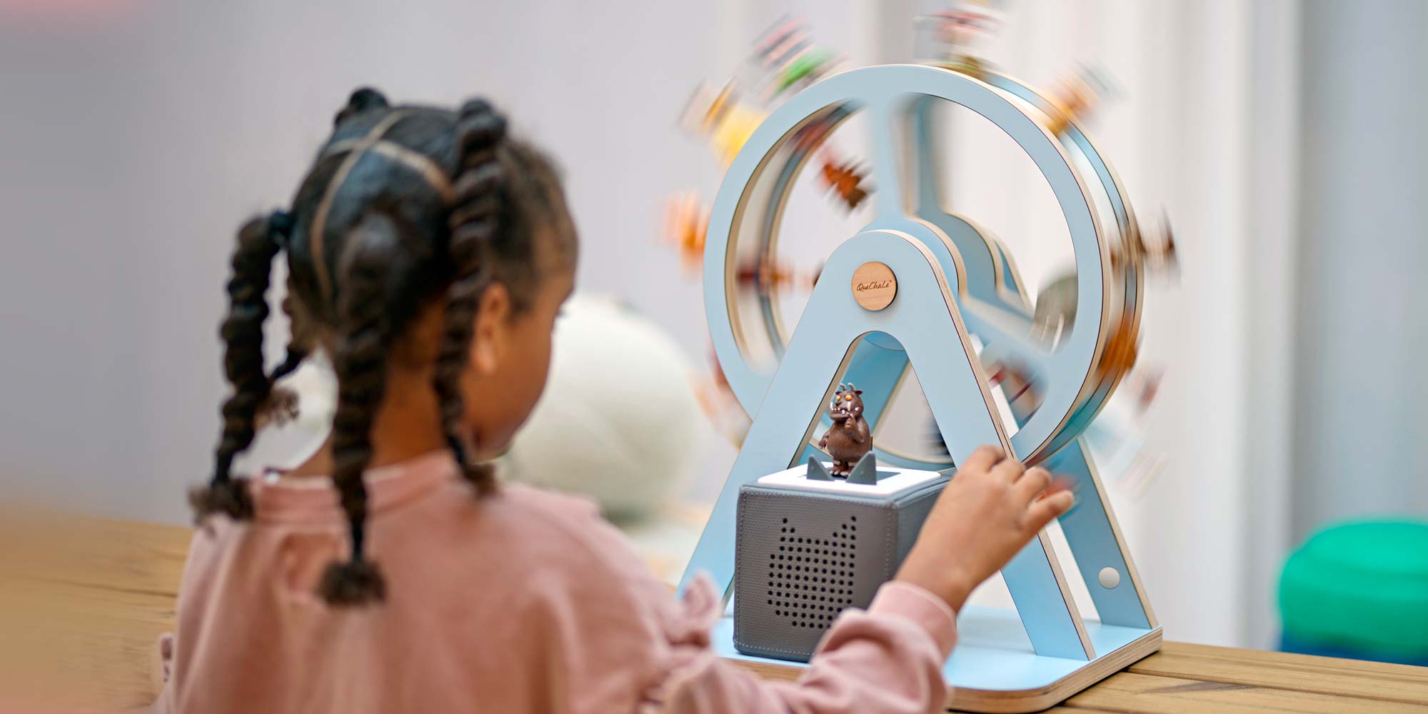 Kind spielt mit dem Glück-Auf-Rad® von QueChaLe, bestückt mit Tonie-Figuren; Toniebox integriert im unteren Bereich, Figuren rotieren im Spiel.